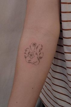 a woman's arm with a small flower tattoo on the left side of her arm