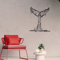 a chair sitting next to a potted plant in front of a wall with a wire sculpture on it