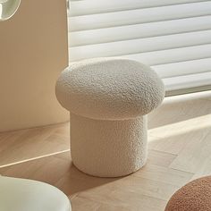 a white stool sitting on top of a hard wood floor next to a window covered in blinds