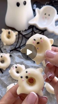 someone is holding some fake white bears in front of other fake ghost like objects on a table