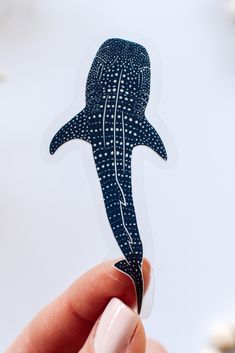 a person holding up a sticker with a whale on it