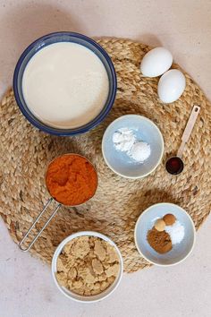 bowls and spoons filled with different types of food on top of a woven place mat