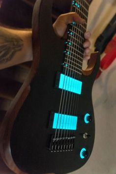 a person holding an electric guitar with blue lights on it's body and neck