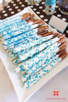 there is a white plate with blue sprinkles and pretzels on it