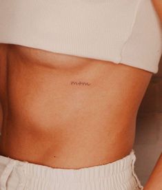 a woman's stomach with the word mom tattooed on her left side ribcage