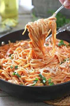 someone using a fork to stir noodles in a skillet