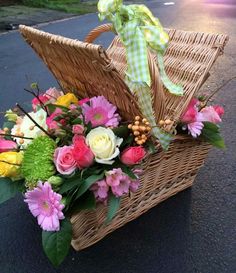 a basket filled with flowers sitting on the side of a road