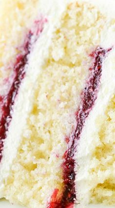 a piece of cake with white frosting and red toppings on it, sitting on a plate