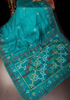 Step into elegance with this Teal Gachi Tussar Silk Saree, featuring exquisite hand embroidery that showcases traditional craftsmanship. The saree is crafted from luxurious Gachi Tussar silk, known for its rich texture and natural sheen, highlighted by a captivating teal hue. Adorned with intricate hand embroidery, the saree displays delicate patterns that add a touch of sophistication and artistry. Complementing the embroidery are detailed Pitta work and mirror accents, which bring a subtle sparkle and enhance the saree's overall allure. Perfect for special occasions and festive celebrations, this saree seamlessly blends classic artistry with contemporary elegance, making it a standout addition to any wardrobe. Ready to wear with fall and pico done. An unstitched blouse fabric is included Luxury Tussar Silk Traditional Wear For Celebrations, Luxury Silk Fabric With Mirror Work Embroidery, Luxury Tussar Silk Traditional Wear With Intricate Embroidery, Luxury Tussar Silk Unstitched Suit With Intricate Embroidery, Luxury Tussar Silk Women's Blouse, Luxury Tussar Silk Suit With Intricate Embroidery, Luxury Tussar Silk Saree With Unstitched Blouse, Luxury Silk Saree For Celebration, Luxury Traditional Tussar Silk Fabric