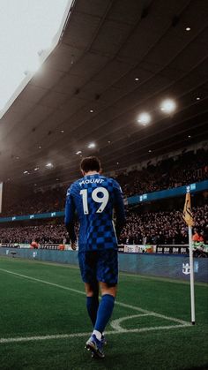 a soccer player is walking towards the goalie's post in front of an empty stadium