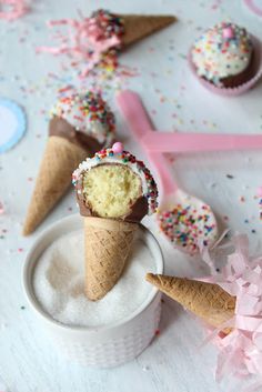 two ice cream cones with sprinkles and pink bows are on a table