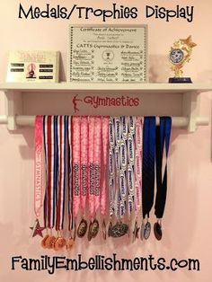 a shelf with medals hanging from it's sides in front of a sign that says medal displays / trophies display