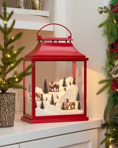 a red lantern sitting on top of a counter next to a christmas tree and potted plant