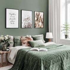 a bedroom with green walls and pictures on the wall above the bed, along with two framed succulents