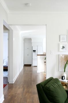 a living room with white walls and wood floors is seen in this image from the hallway