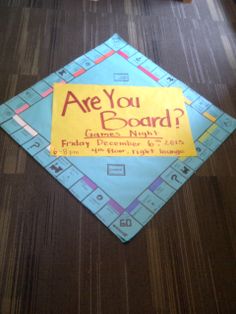 a paper sign that says are you board? on the floor next to a table