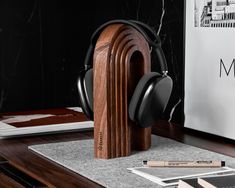 the headphones are sitting on top of a wooden stand next to some pens and pencils