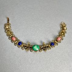 "Vintage Book Chain Bracelet, Gold Tone Green Blue Pink Cabochons Pearls Bracelet, Victorian Revival Jewelry, Gift for her. Era: After MidCentury. Designer: Unsigned. Measurements: - Length: 7 1/4\"inches. - Width: 1/2\" inch. Details: -Metal Color: Gold. - Embellishments: Gold Tone Plating, Faux Pearls, Floral Pattern, Oval Green, Blue, Pink Matte Cabochons. - Closure: FoldOver Claps. Here are more Vintage Jewelry items for your viewing pleasure: https://etsy.me/2SGhTFo Our shop team members do Vintage Multicolor Jeweled Bracelets, Multicolor Cabochon Costume Jewelry, Blue Vintage Nickel Free Bracelets, Vintage Blue Nickel-free Bracelets, Vintage Multicolor Metal Beaded Bracelets, Vintage Blue Nickel-free Bracelet, Vintage Multicolor Cabochon Jewelry, Vintage Multicolor Charm Bracelet, Ornate Multicolor Bracelets For Gifts