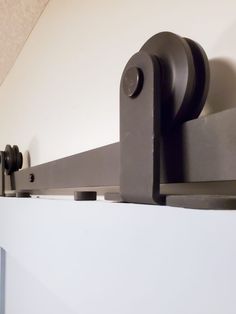 a close up of a curtain rod on a white wall with black handles and knobs