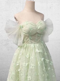 a dress on a mannequin with flowers in the front and green petals on the back