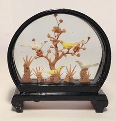 there is a small tree with birds in the glass case on top of this stand