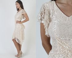 "Vintage 80s sheer ivory floral lace dress. V neck wrap style bodice with fluttery sleeves. Gathered and fitted waist with sweeping, tulip hi lo skirt. Dress is lined and zips up the back. size estimate: S shoulders: 17.5\" bust: 30\" waist: 28\" hips: 30\" total length: 35\"-42\" Model is 5'9\" and measures 33\" bust, 25\" waist, 33\" hips. Belts/accessories are not included unless noted in the description." Fitted Lace Dress With Ruffles For Wedding Guests, Fitted V-neck Lace Dress For Wedding Guest, Fitted Short Sleeve Lace Dress With Delicate Lace, Delicate Lace Fitted Dress With Short Sleeves, Fitted Short Sleeve Delicate Lace Dress, Fitted V-neck Lace Wedding Dress, Vintage Lace V-neck Dresses, Elegant V-neck Dress For Vintage Events, Fitted V-neck Lace Bridesmaid Dress