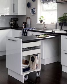 a kitchen with white cabinets and black counter tops is shown in this image, there are plates hanging on the wall