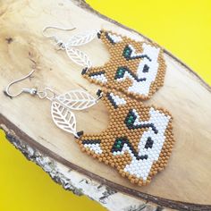 two beaded fox earrings sitting on top of a piece of wood