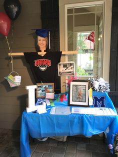 there is a table with pictures and balloons on it that have been placed in front of the house