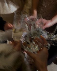 several people are holding wine glasses in the middle of a toasting party with white and gold confetti on them