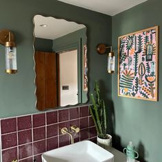 a bathroom with a sink, mirror and potted plant on the counter in front of it