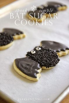 some cookies with chocolate frosting and sprinkles are on a baking sheet