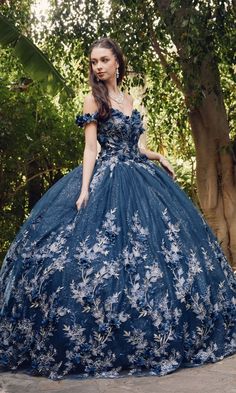 a woman in a blue dress standing next to a tree