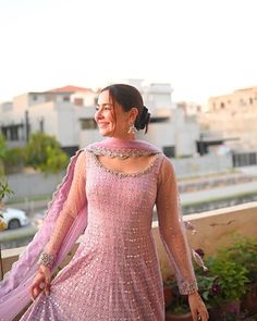 a woman in a pink dress standing on a balcony