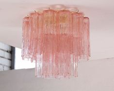 a pink chandelier hanging from the ceiling in a room with white walls and windows