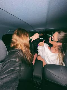 two women sitting in the back seat of a car