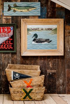 three framed pictures hang on the wall next to two baskets with fishing related items in them