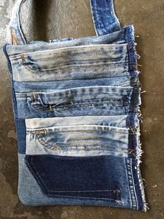 several different colored jeans are stacked in a pocket on the floor and one is torn open