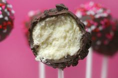 chocolate covered cake pops with white frosting and sprinkles on pink background