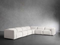 a large white couch sitting on top of a floor next to a gray wall in an empty room