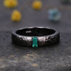 a black ring with a green stone in the middle