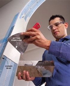 a man is working on the side of a wall with some tape and a pair of scissors