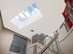 an indoor stair case with glass railings and skylight above the stairs in a modern home