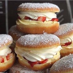 a pile of doughnuts with frosting and strawberries on them