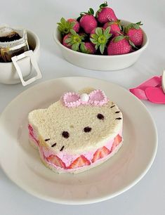 a hello kitty sandwich on a plate with strawberries