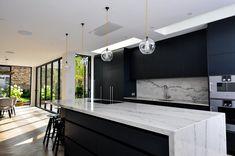 a modern kitchen with marble counter tops and black cabinets, along with an island in the middle