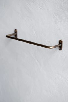 a metal towel rack mounted to the side of a wall with two hooks on it