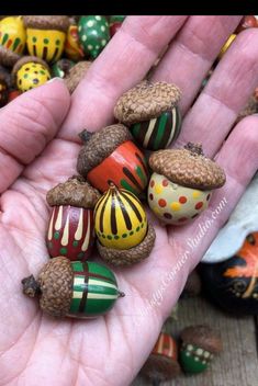 a hand is holding some colorfully painted acorns