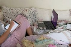 a person laying on a couch with a laptop and book in their hands, reading