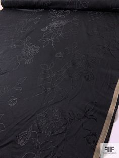 a black table cloth with flowers on it and a roll of fabric next to it